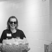 Black and white picture of Alumna carrying water bottles